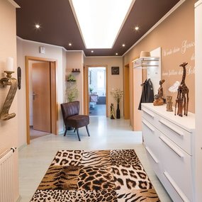 Heller Flur mit afrikanischen Dekofiguren, Tierfellteppich und moderner Einrichtung.