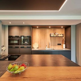Moderne Küche mit dunklen Fronten, Holzarbeitsfläche und stilvoller LED-Beleuchtung.