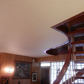 Moderne Holztreppe mit Edelstahlgeländer in einem wohnlichen Flur mit Wandbildern.