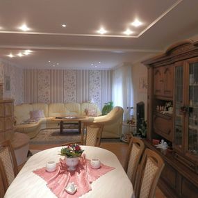 Helles Wohnzimmer mit gemütlicher Sitzecke, Esstisch, Holzschrank und Dekoration.